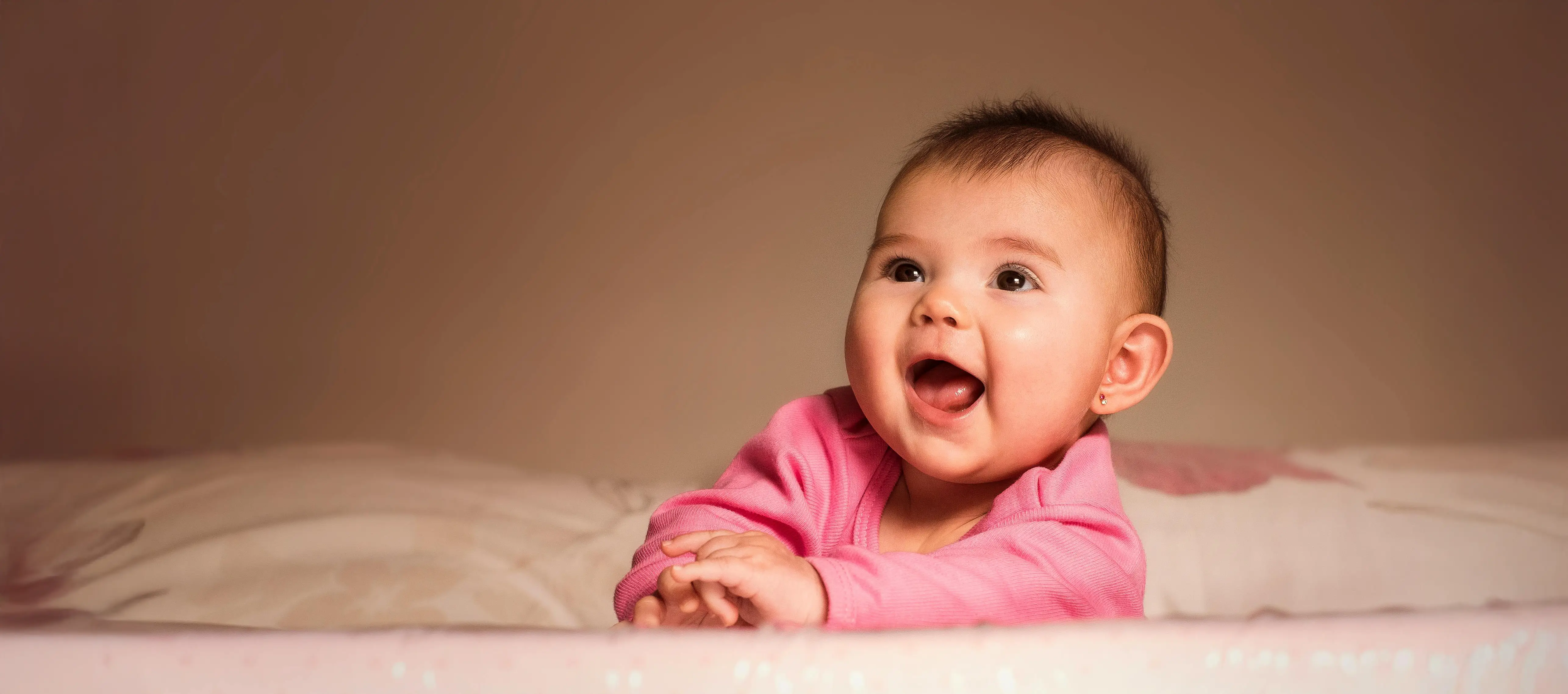 smiling baby playing on a bed