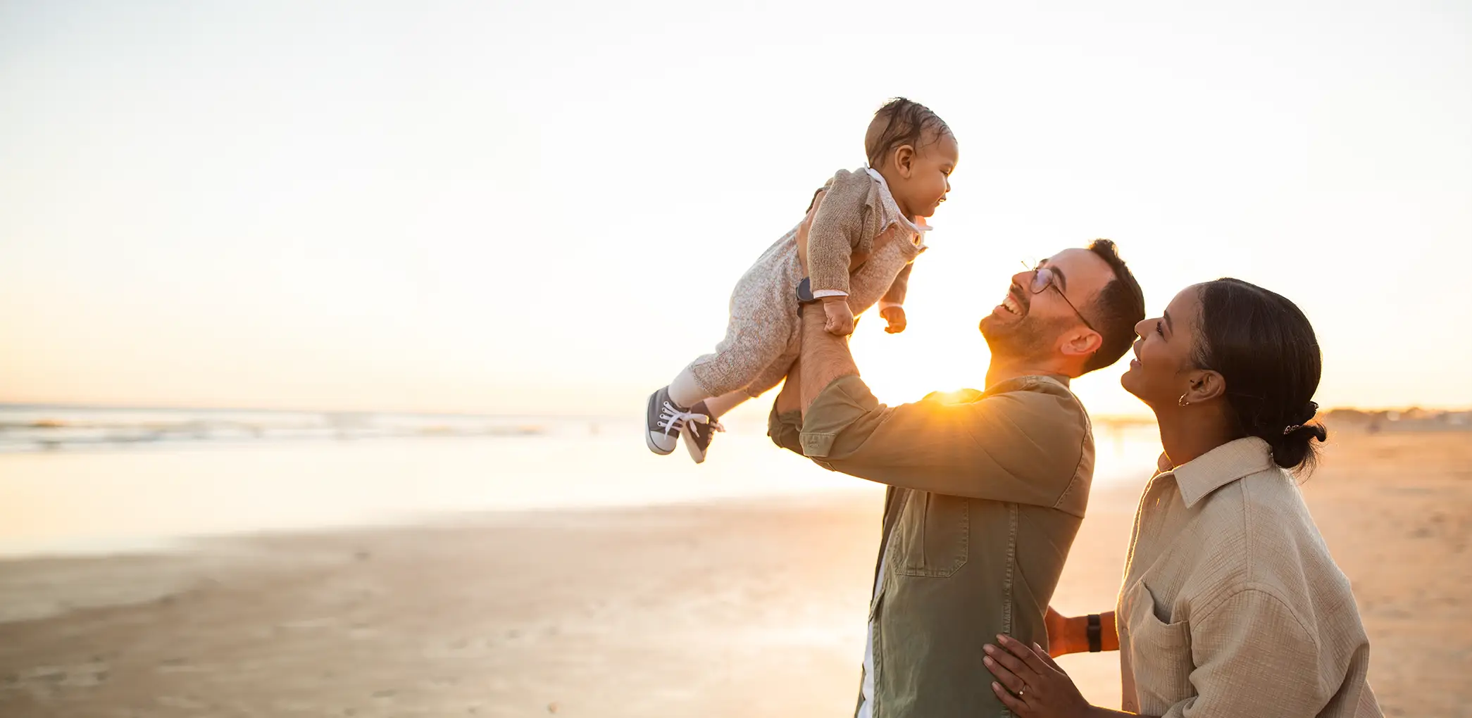 happy jewish parents and baby hanging out at a beach