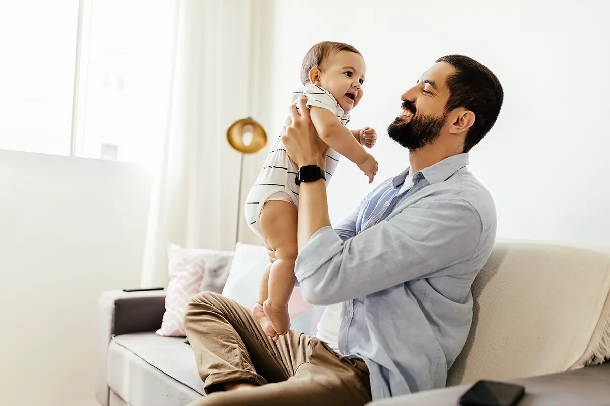 dad playing with his baby son on a couch in the living room-mobile