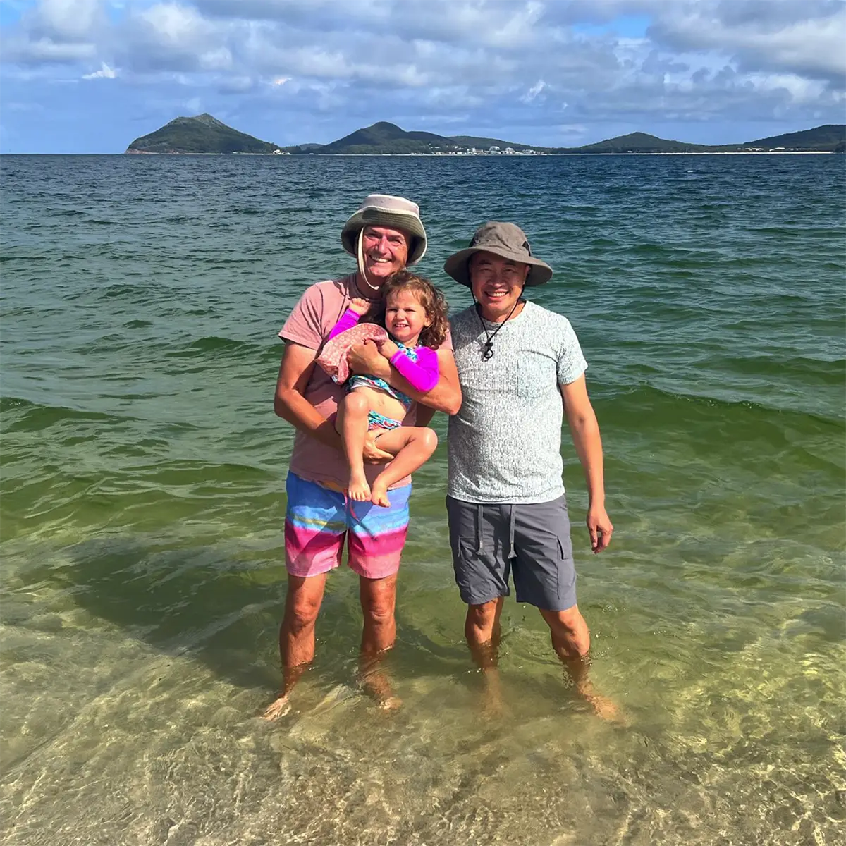 gay couple with their daughter on vacation at a beach